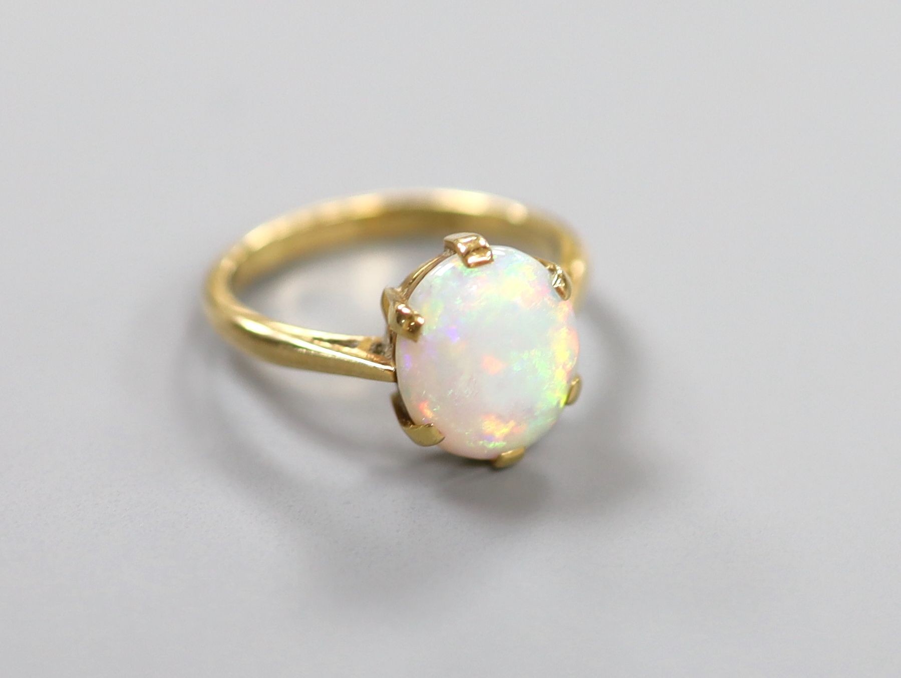 An 18ct and oval white opal set ring, size N, gross weight 3.6 grams.